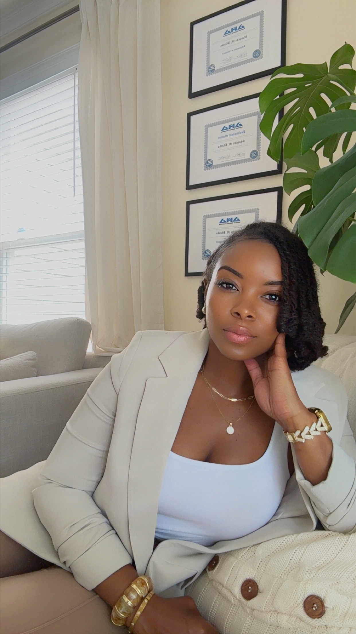 Monique Blanks in a cream suit, resting her hand gently against her face